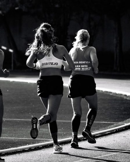 Black and white back view of unrecognizable fit female runners in sportswear running during track and field competition
